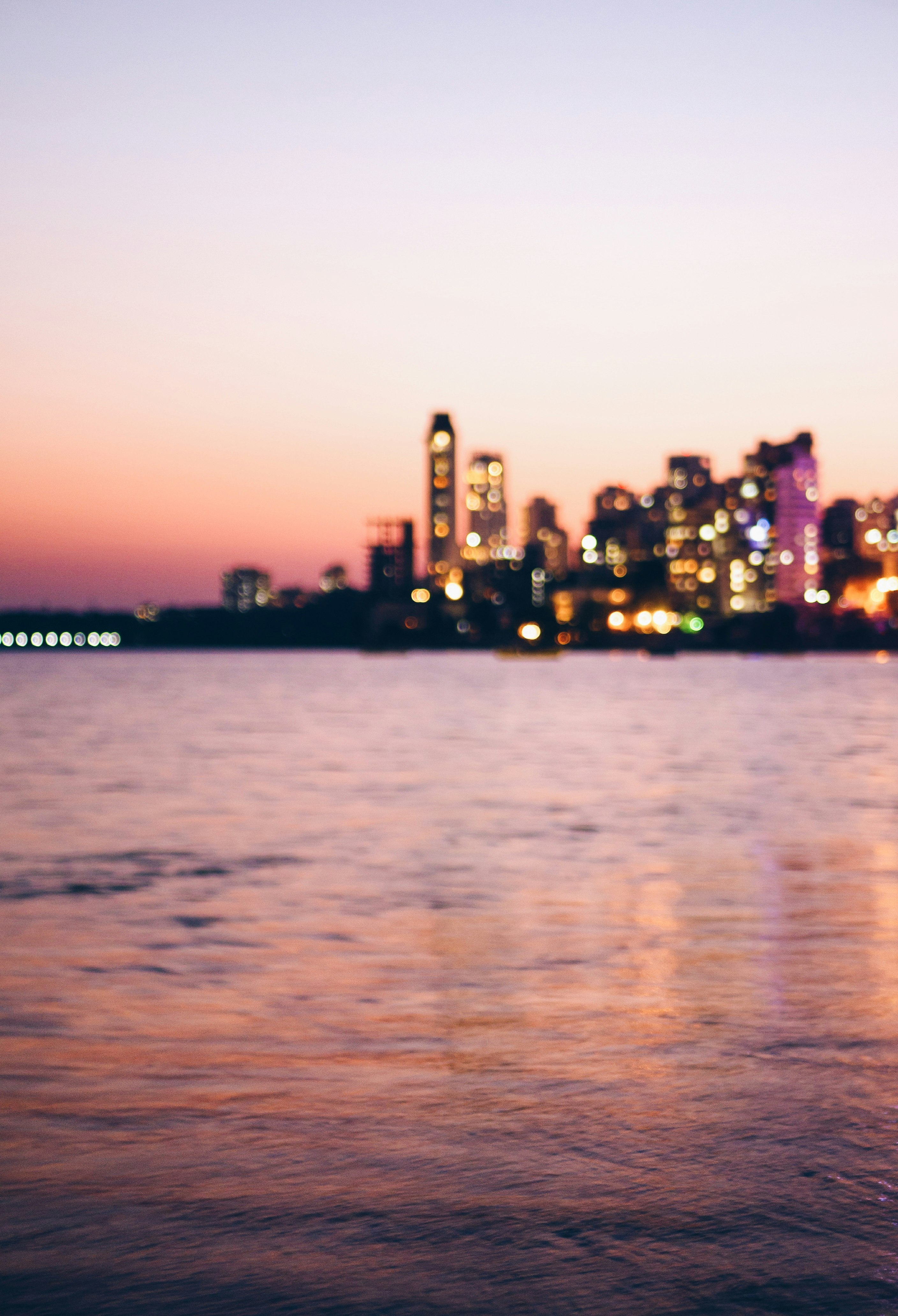 landscape photography of lighted buildings beside body of water